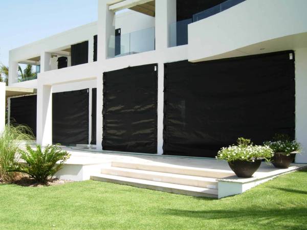 A large white house with black curtains, equipped with hurricane protection features for safety during storms.