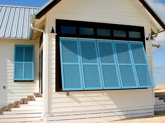 Hurricane shutters installed on white siding house