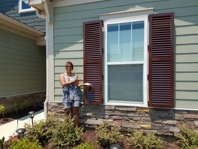 Classic Colonial shutters open on a traditional Florida home, showcasing elegant hurricane protection.